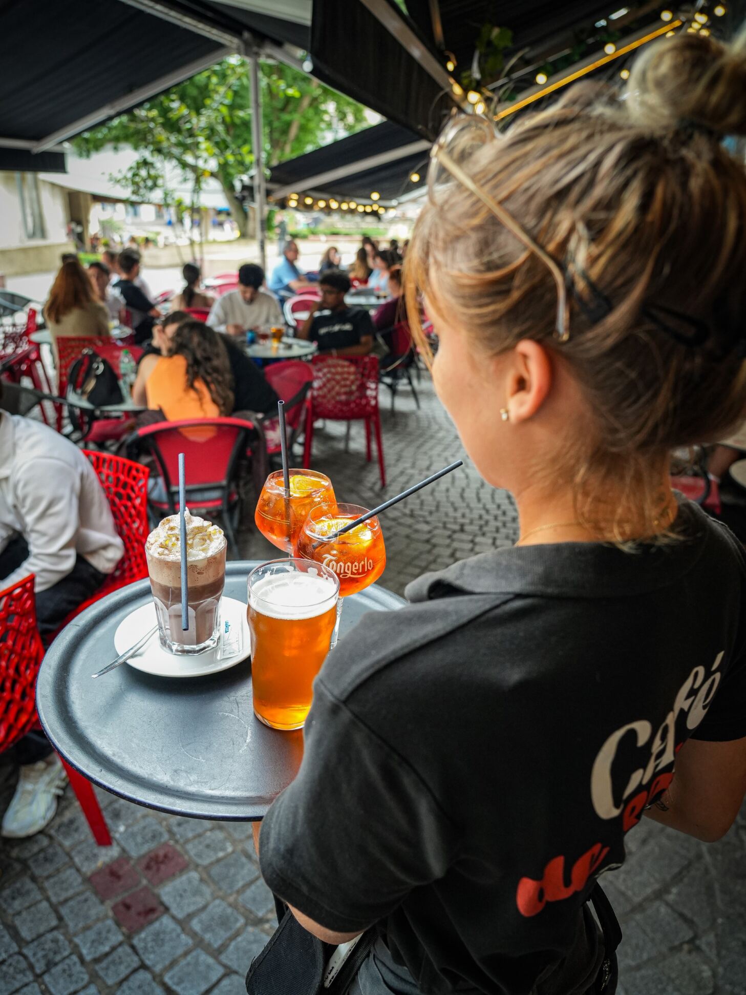 Une serveuse apporte des boissons en terrasse